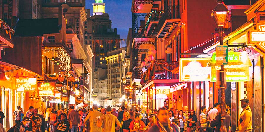 A busy night on Bourbon Street, full of tourists and bright lights.